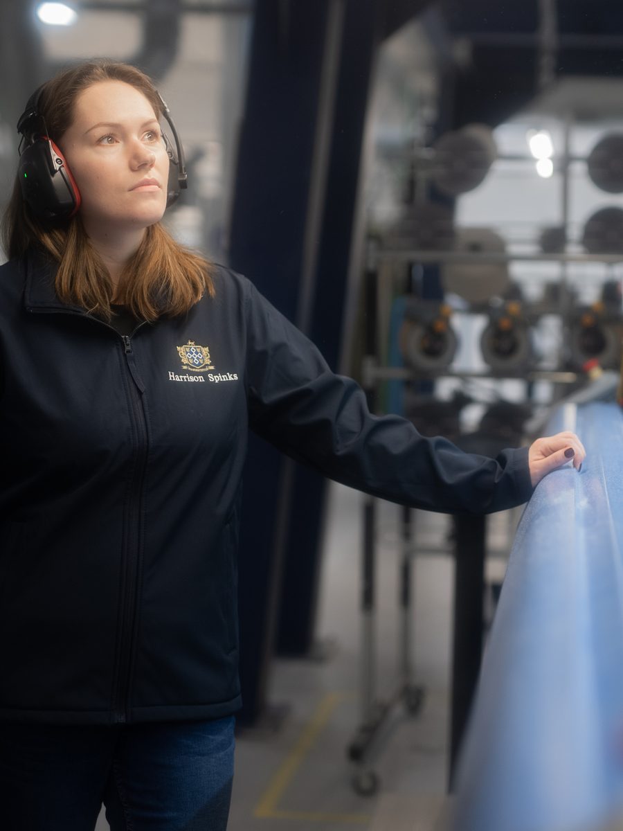 A Harrison Spinks weaver next to the loom that makes their mattress fabric