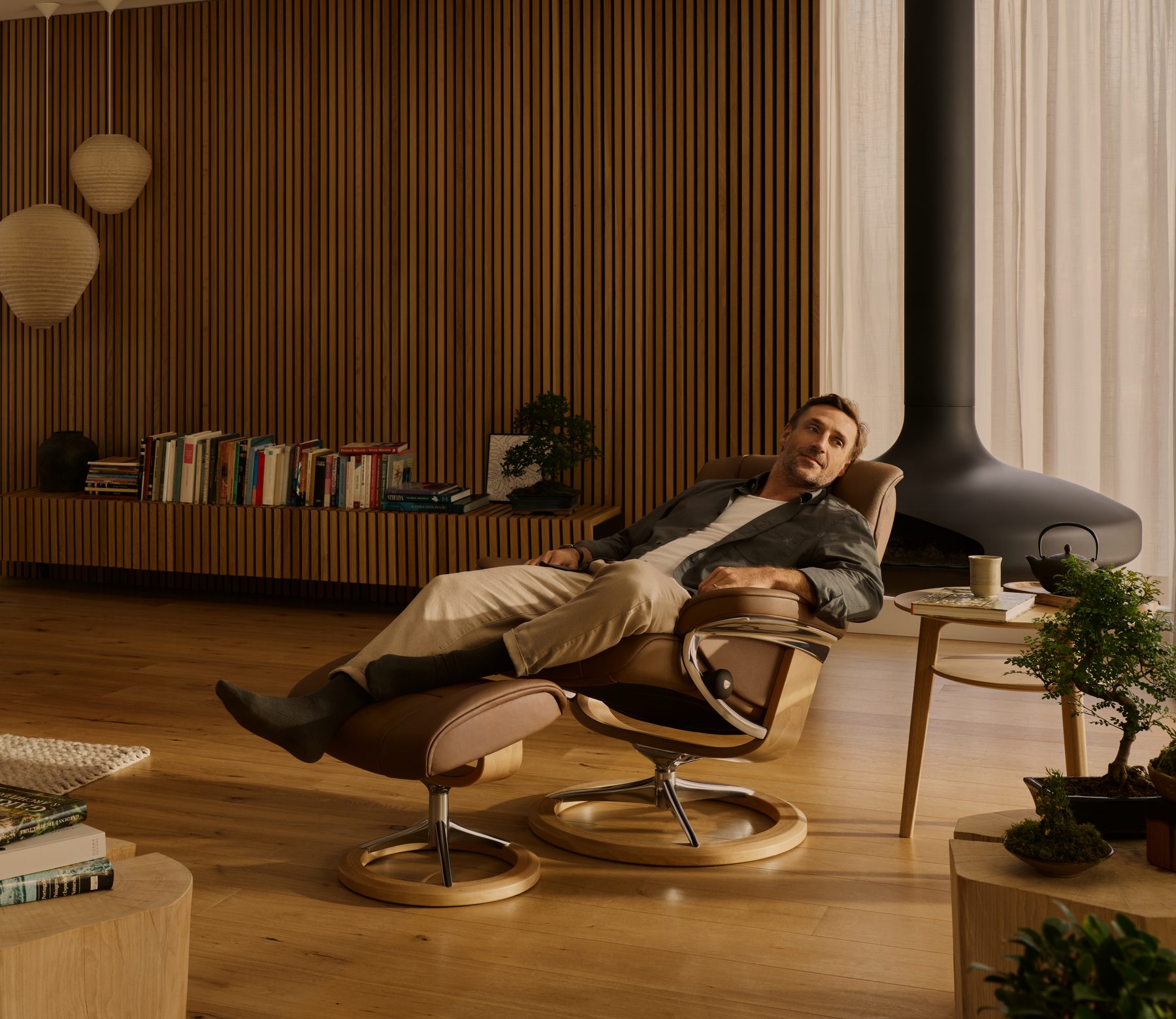 Man reclining in a Stressless® Mayfair recliner in a living room with afternoon light